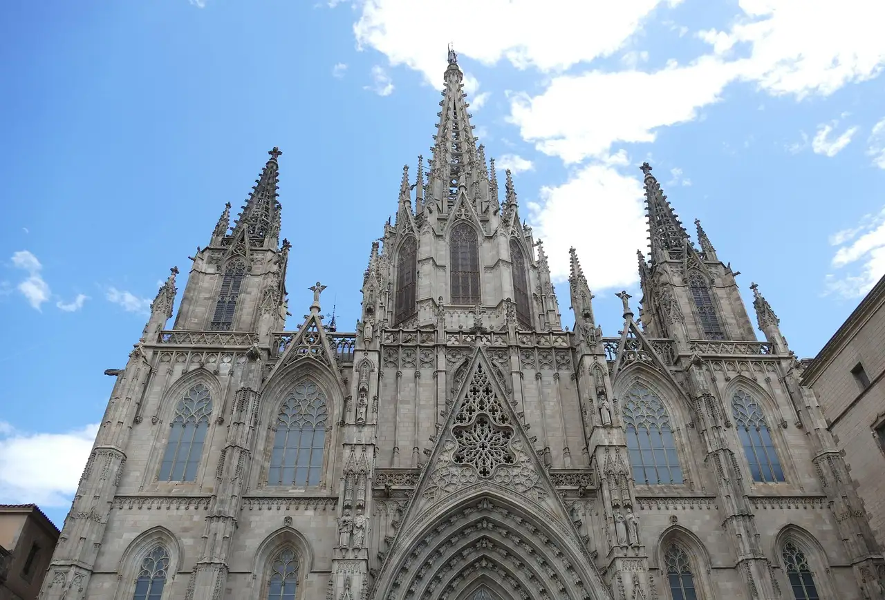The pointed Gothic spires and carved front of Barcelona Cathedral under a blue sky