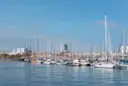 Sailboats and yachts moored in Barcelona's harbor under a blue sky