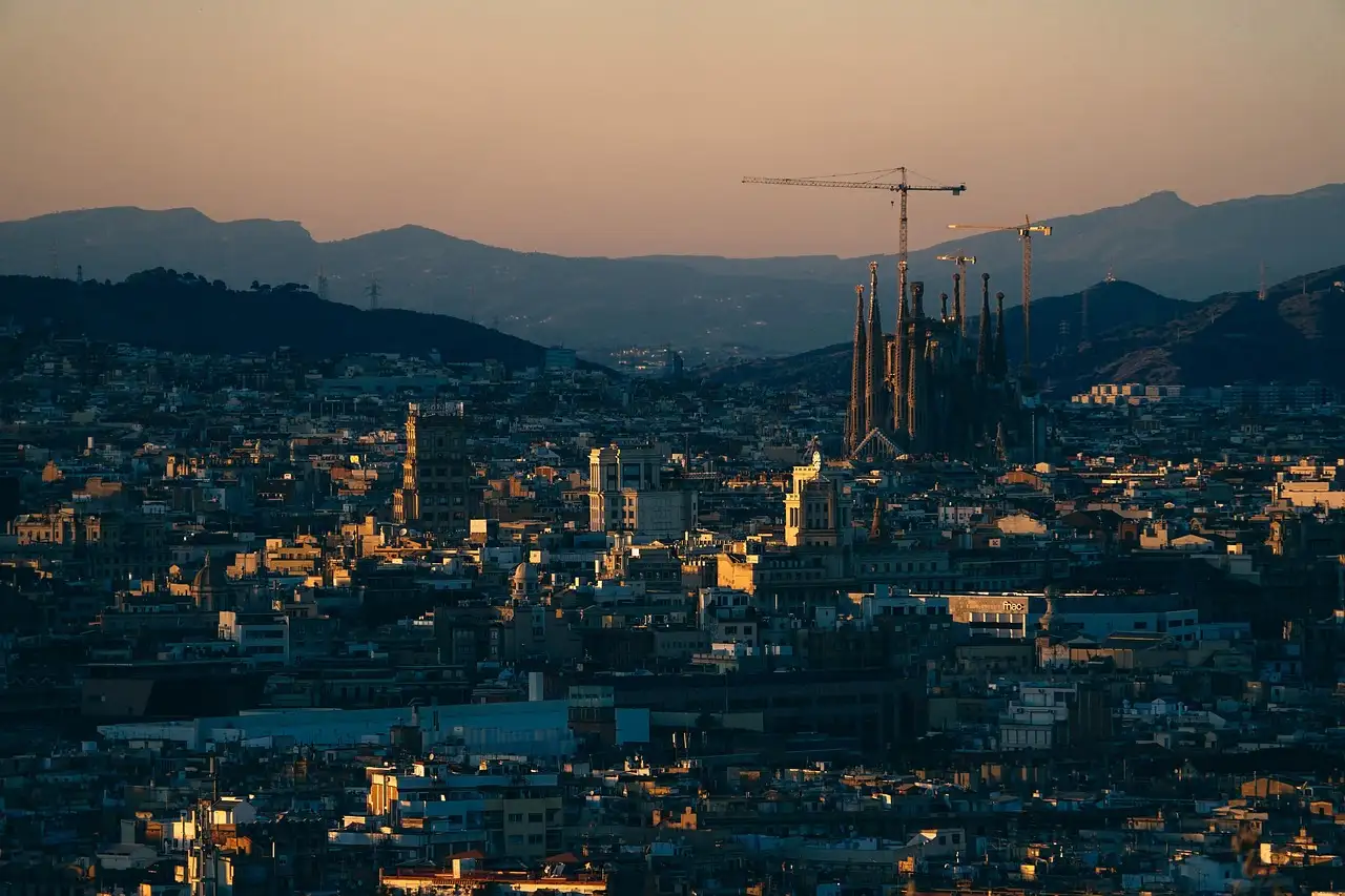 Barcelona at dusk, with the Sagrada Família and its cranes against the hills