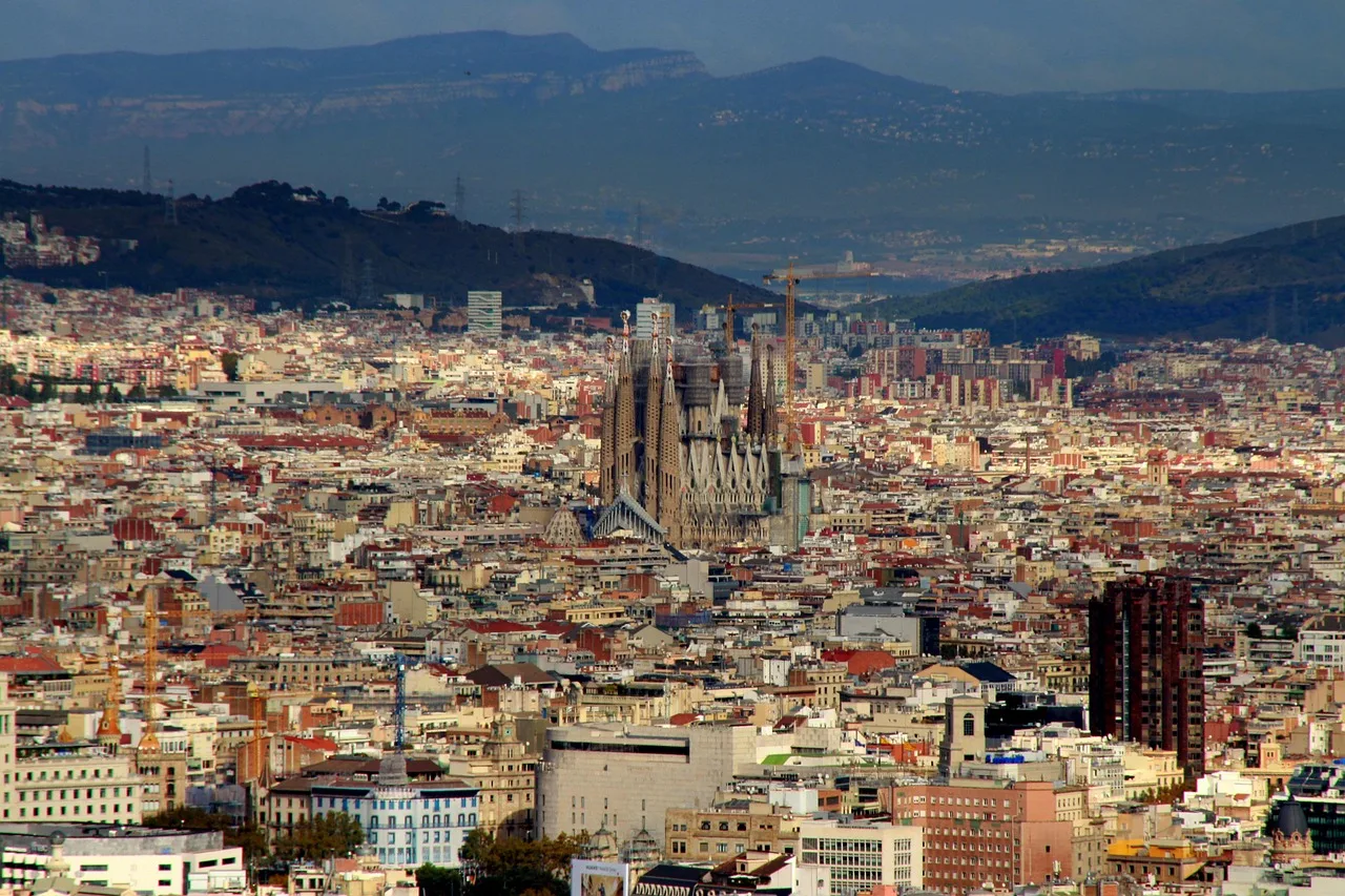 The Sagrada Família rising above the rooftops of Barcelona, with green hills behind