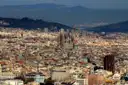 The Sagrada Família rising above the rooftops of Barcelona, with green hills behind