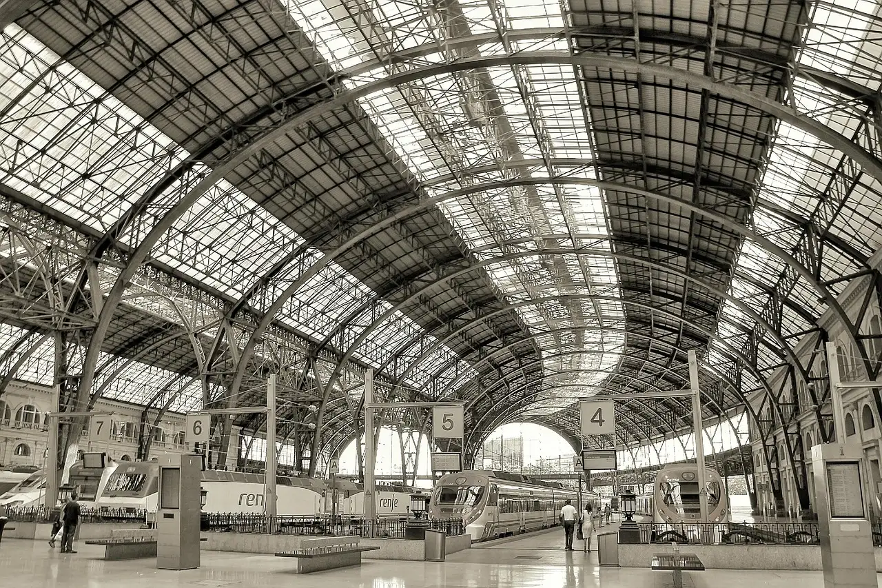 Passenger trains under the iron-and-glass roof of a Barcelona railway station