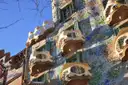 Mask-shaped balconies on the blue mosaic front of Casa Batlló, seen from below