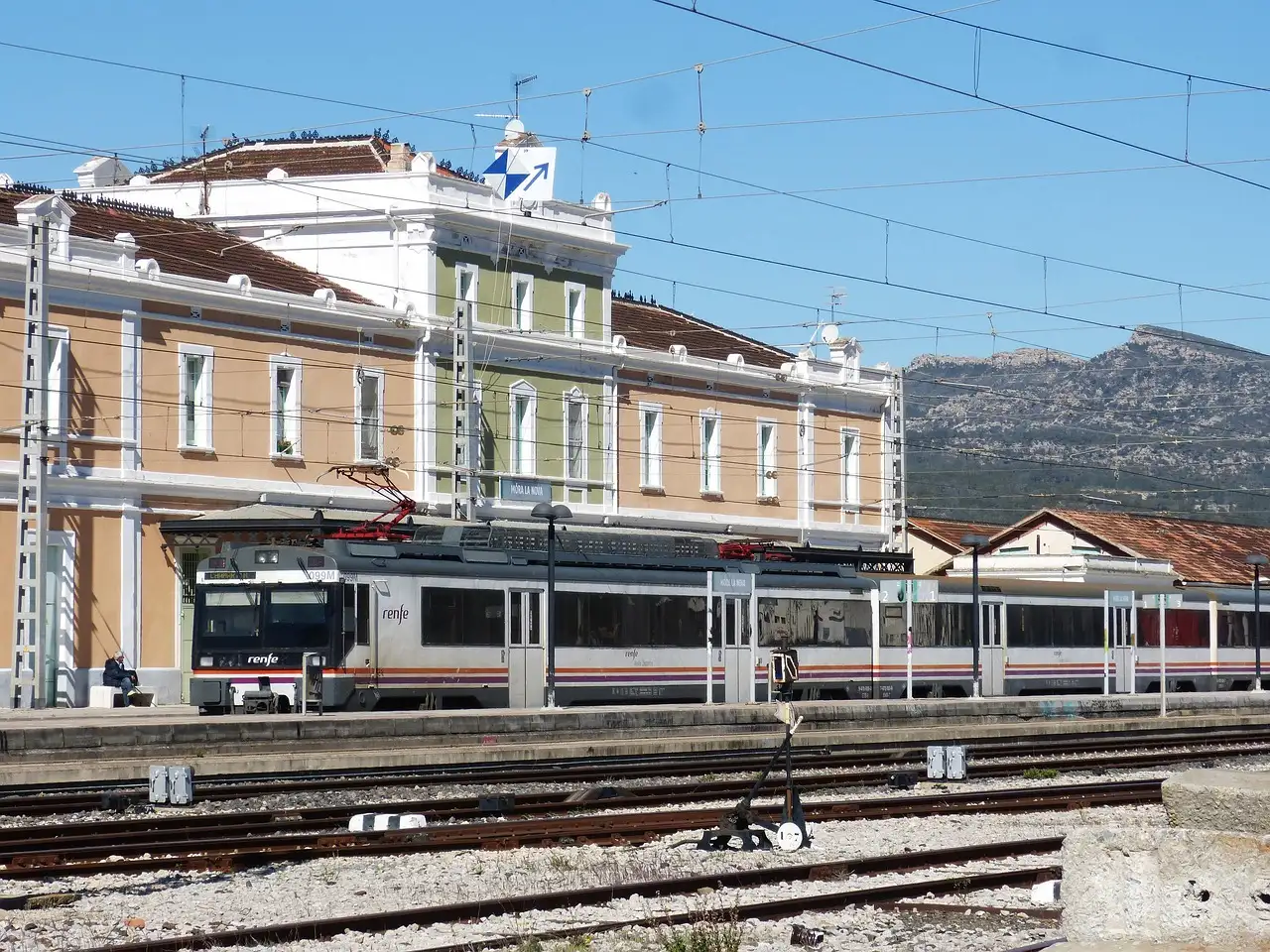 A regional train at a Spanish station platform with mountains behind