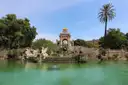 The Cascada fountain in Parc de la Ciutadella behind a green pond and palm trees