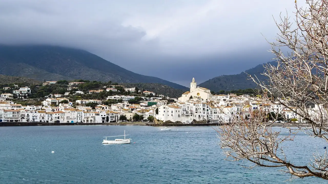 The white houses of Cadaqués around a calm bay, with hills behind
