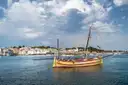 A wooden sailboat moored in the bay of Cadaqués, with the white town behind