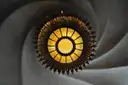 A swirling plaster ceiling with a round sun-shaped lamp in the middle, inside Casa Batlló