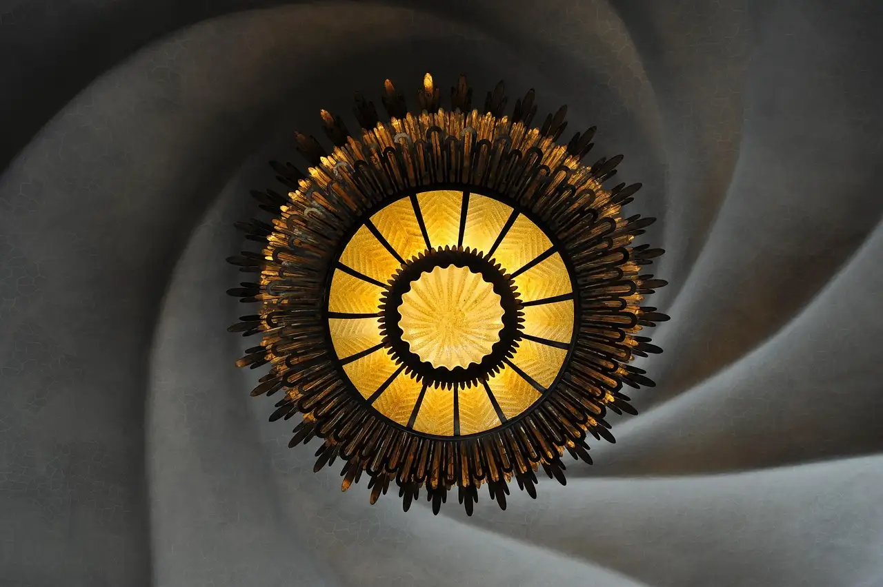 A swirling plaster ceiling with a round sun-shaped lamp in the middle, inside Casa Batlló