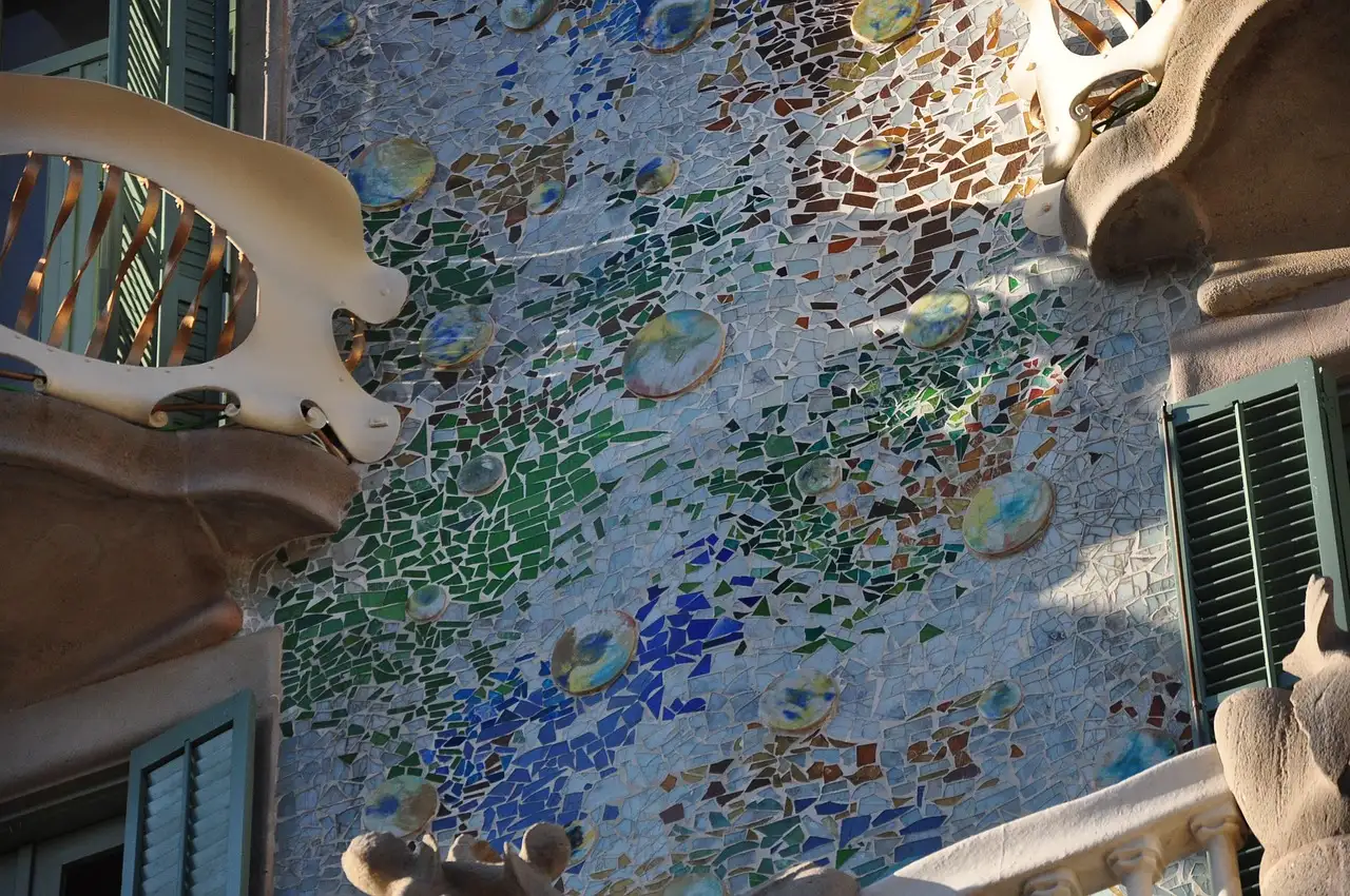 Close view of Casa Batlló's mosaic wall in blue and green with a pale balcony