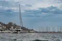 Sailing catamaran on the sea near a marina on a cloudy day