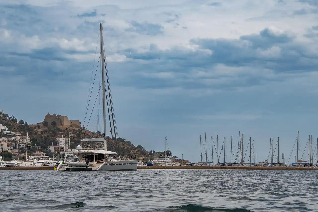 Sailing catamaran on the sea near a marina on a cloudy day