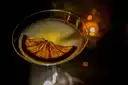 Cocktail with an orange slice in a coupe glass on a dark bar