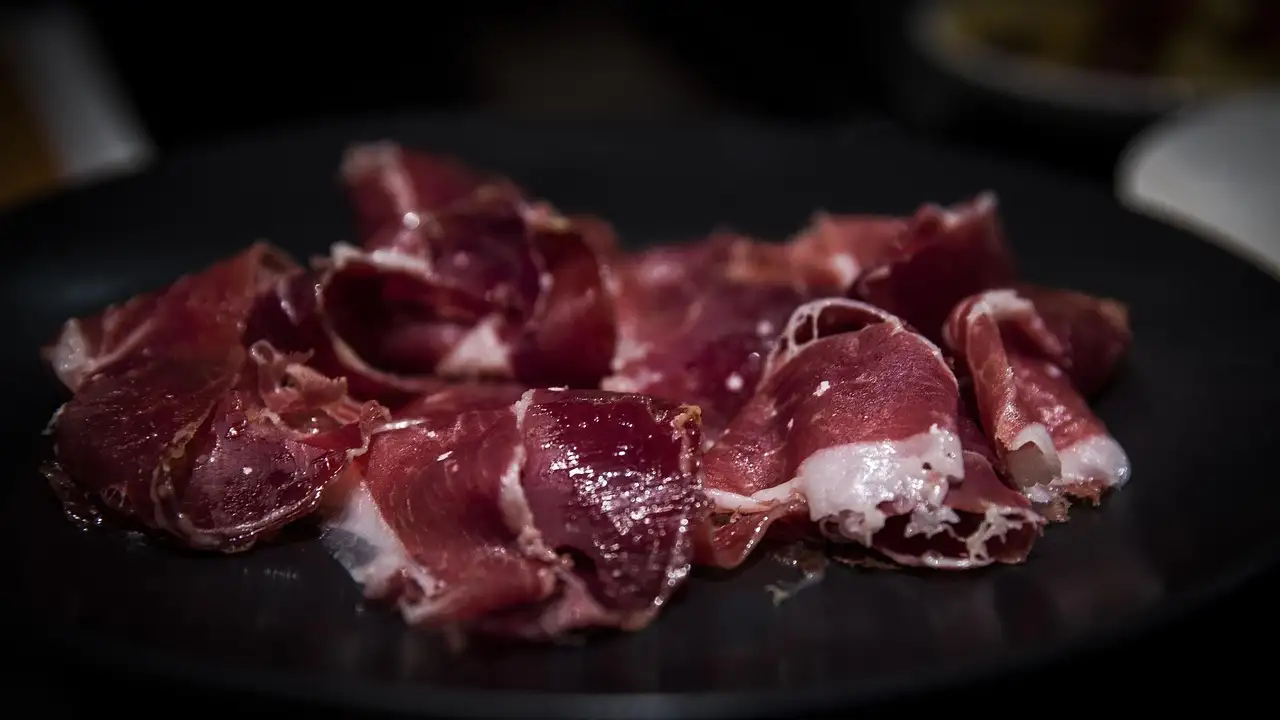 Thin slices of cured jamon on a dark plate