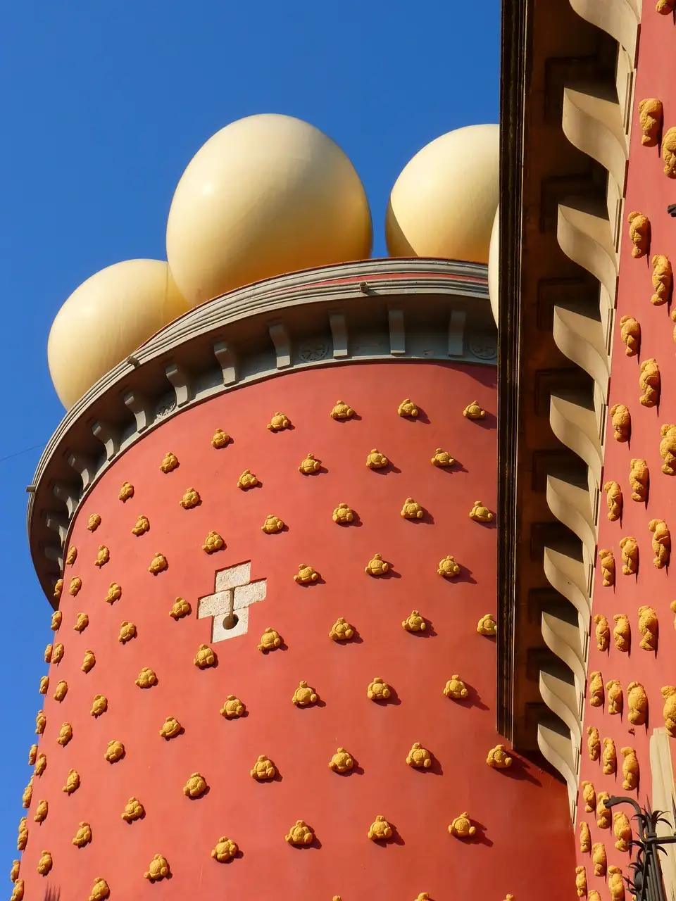 A round red tower of the Dalí Theatre-Museum with giant eggs on top