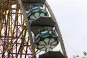 Close view of a big wheel with its round gondolas against a pale sky