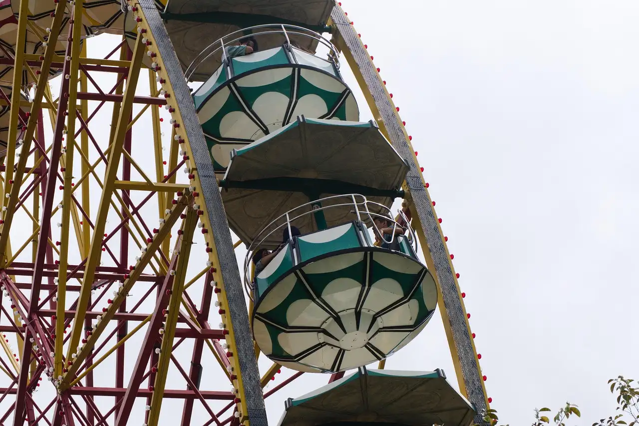 Close view of a big wheel with its round gondolas against a pale sky