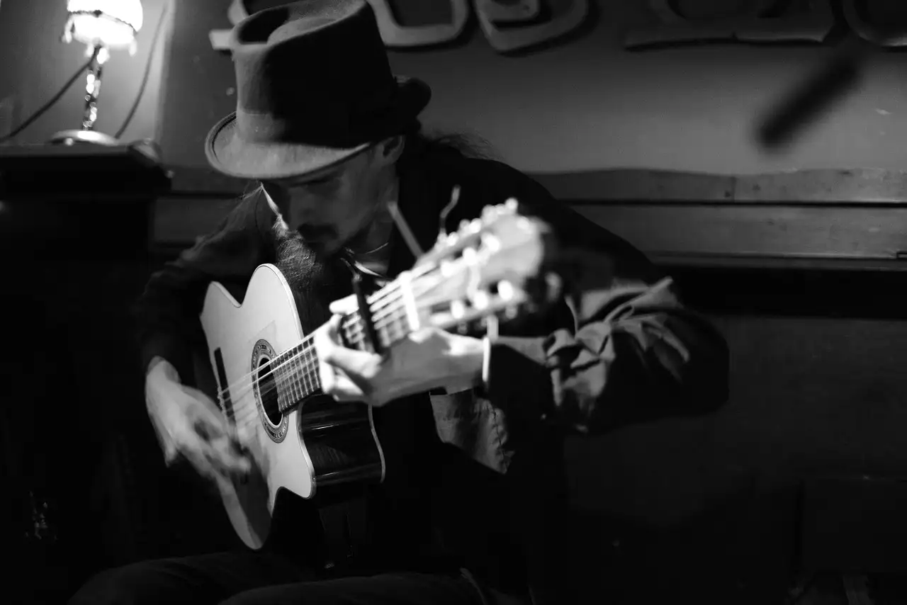 Guitarist playing a classical Spanish guitar in a dim room