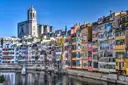 Colorful houses along the Onyar river in Girona, with the cathedral tower above them