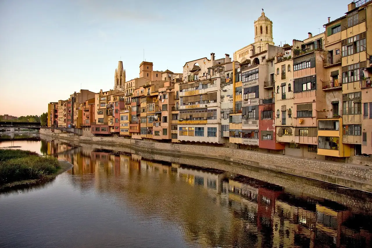 Painted houses and the cathedral of Girona reflected in the Onyar river at sunset