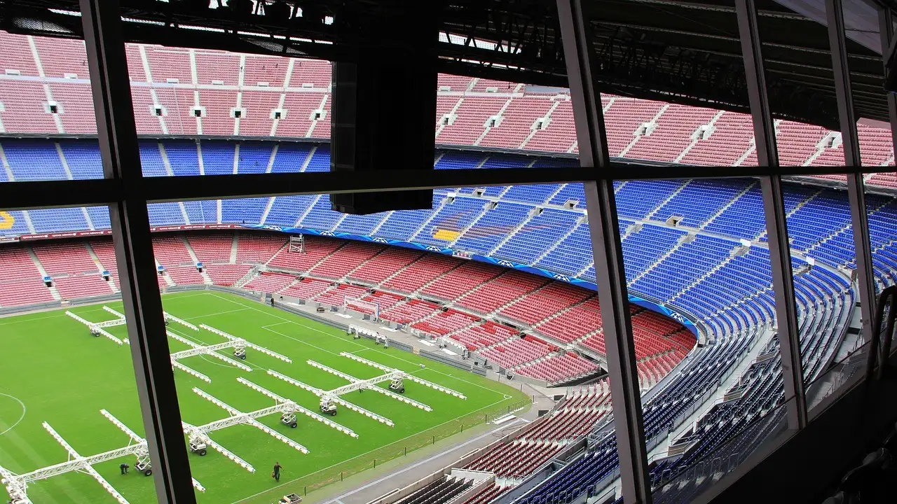 The empty red and blue seats of the Barcelona football stadium, seen through a window