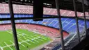 The empty red and blue seats of the Barcelona football stadium, seen through a window