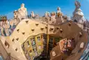 A wide-angle view over the curving roof terrace and chimneys of La Pedrera, with the courtyard below
