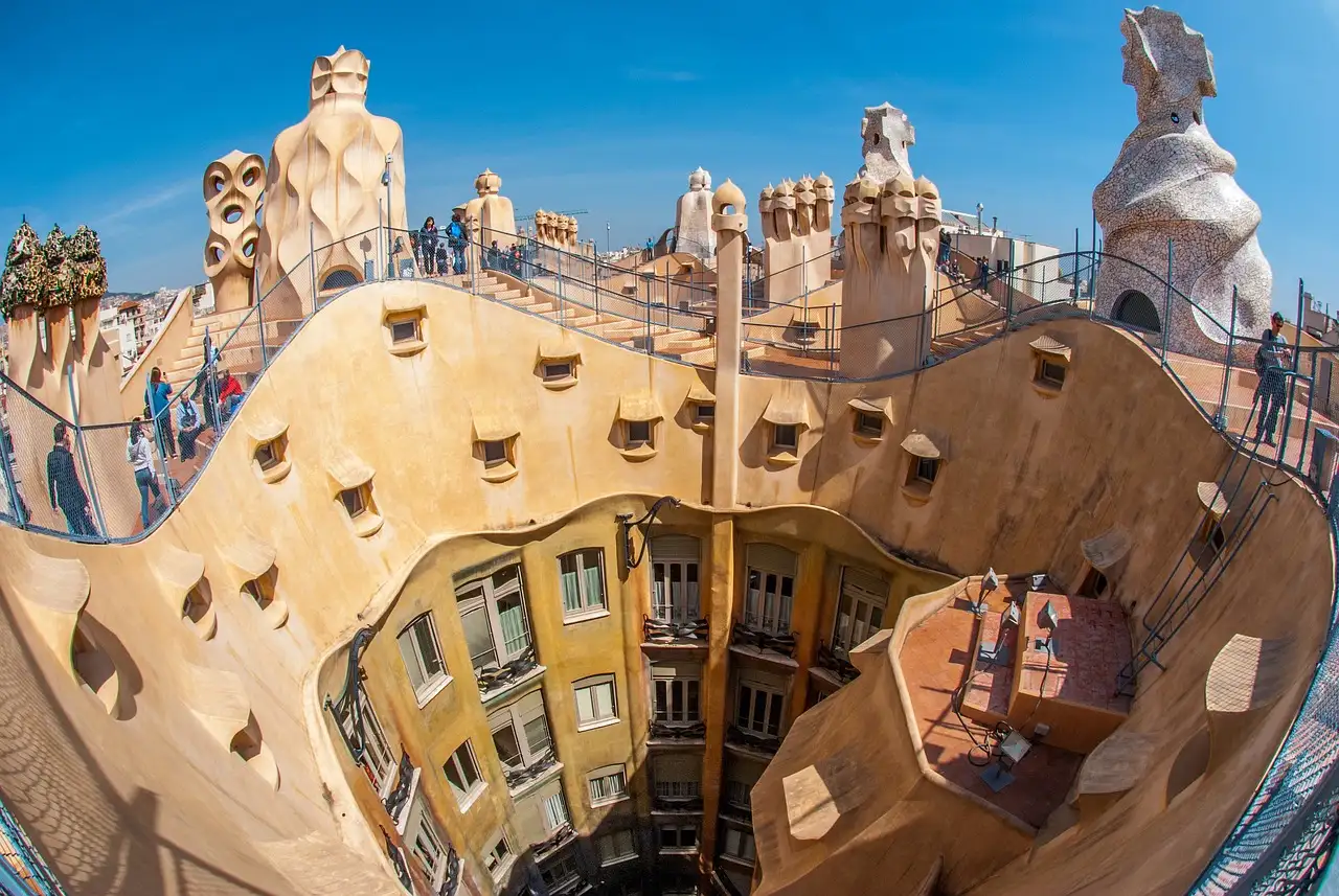 A wide-angle view over the curving roof terrace and chimneys of La Pedrera, with the courtyard below