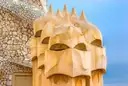 Sand-colored chimneys shaped like helmeted heads on the roof of La Pedrera