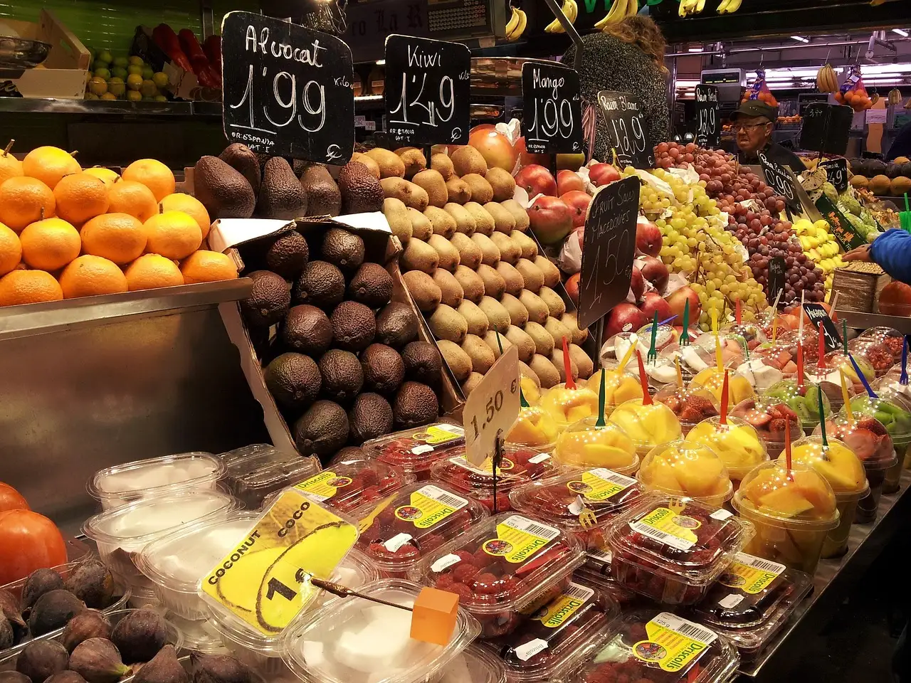 Fruit stall at La Boqueria with oranges, avocados and fruit cups