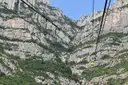 A small yellow cable car climbing past the steep rock walls of Montserrat
