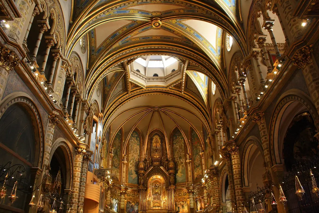 The long nave of the Montserrat basilica with its painted ceiling and gold altar