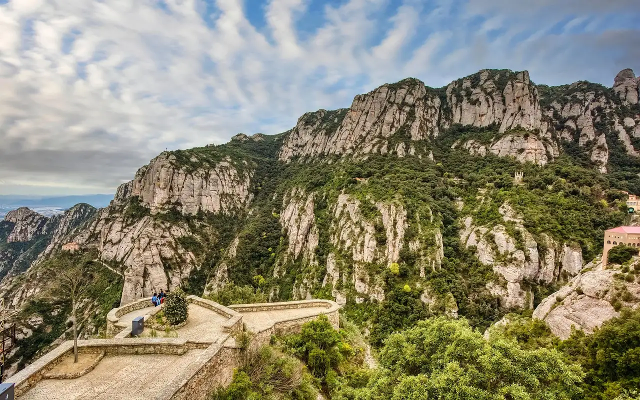 A stone viewpoint and path on the green cliffs of Montserrat under a cloudy sky