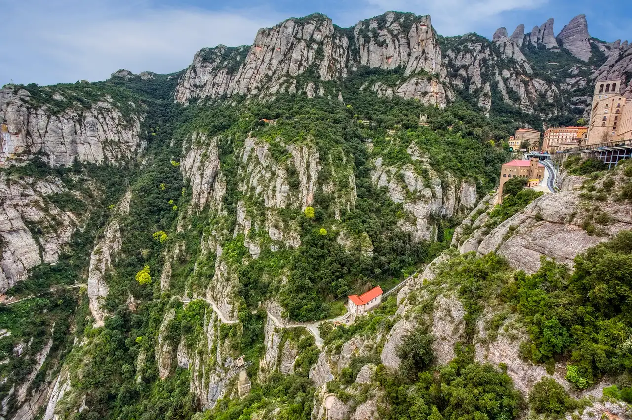 The monastery of Montserrat tucked under grey cliffs above a green valley