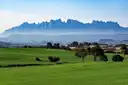 The jagged ridge of Montserrat above green fields and trees in the morning haze