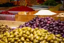 Green and purple olives piled on a market stall