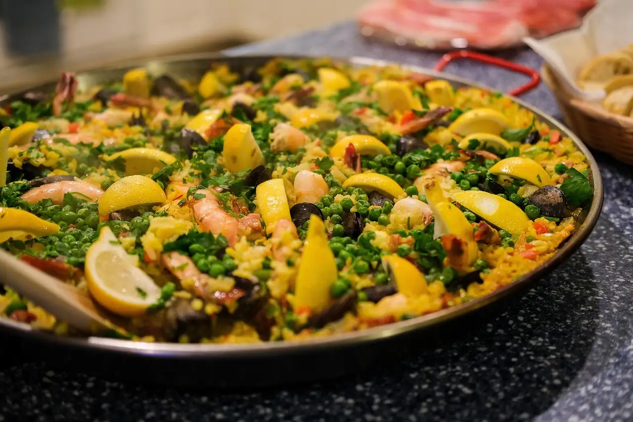 Finished seafood paella with lemon wedges and peas