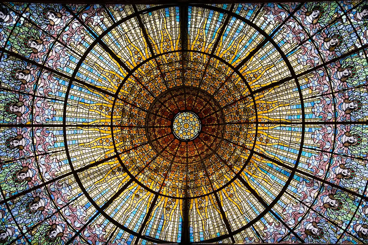 A round stained-glass skylight in gold, orange and blue, seen from below