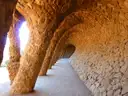 A curving stone arcade with leaning columns in Park Güell