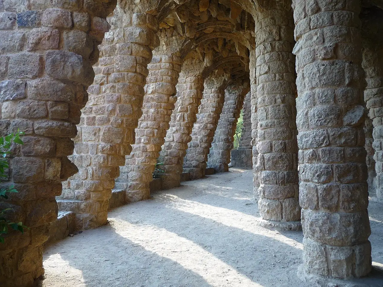 A row of rough stone columns holding up a covered walkway in Park Güell