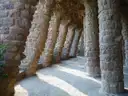 A row of rough stone columns holding up a covered walkway in Park Güell
