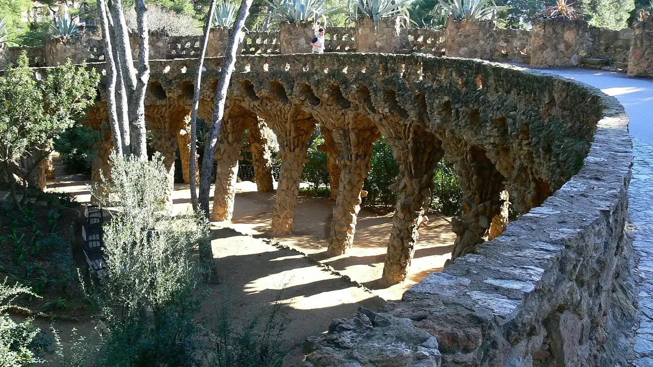 A stone path on leaning columns among trees in Park Güell