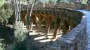 A stone path on leaning columns among trees in Park Güell