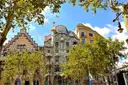 Casa Batlló and its neighbor on Passeig de Gràcia, framed by green trees and street lamps