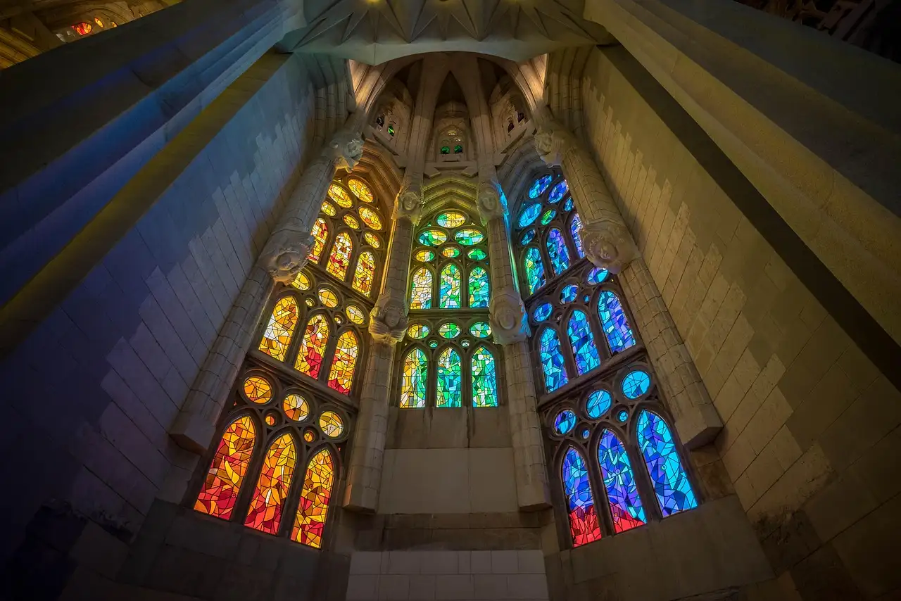 Green, blue and red stained-glass windows glowing inside the Sagrada Família