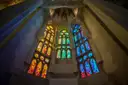 Green, blue and red stained-glass windows glowing inside the Sagrada Família
