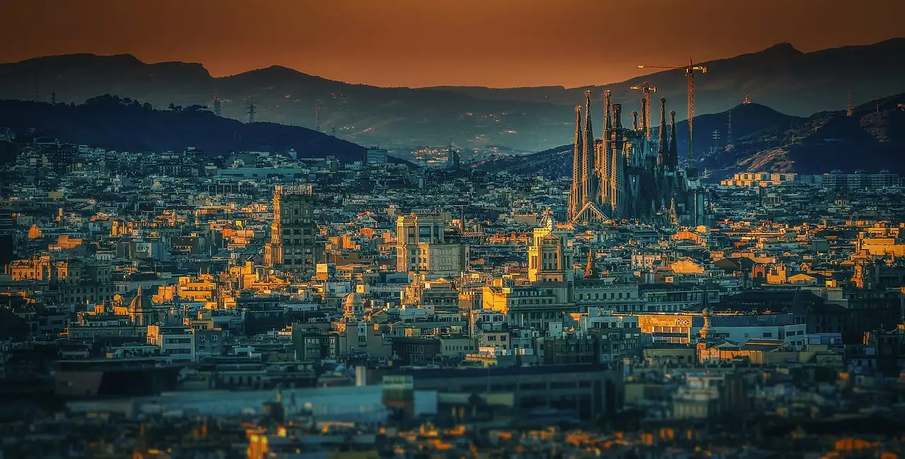 A Barcelona street at dusk leading toward the spires of the Sagrada Família