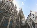 The carved stone towers of the Sagrada Família seen from below against a bright sky