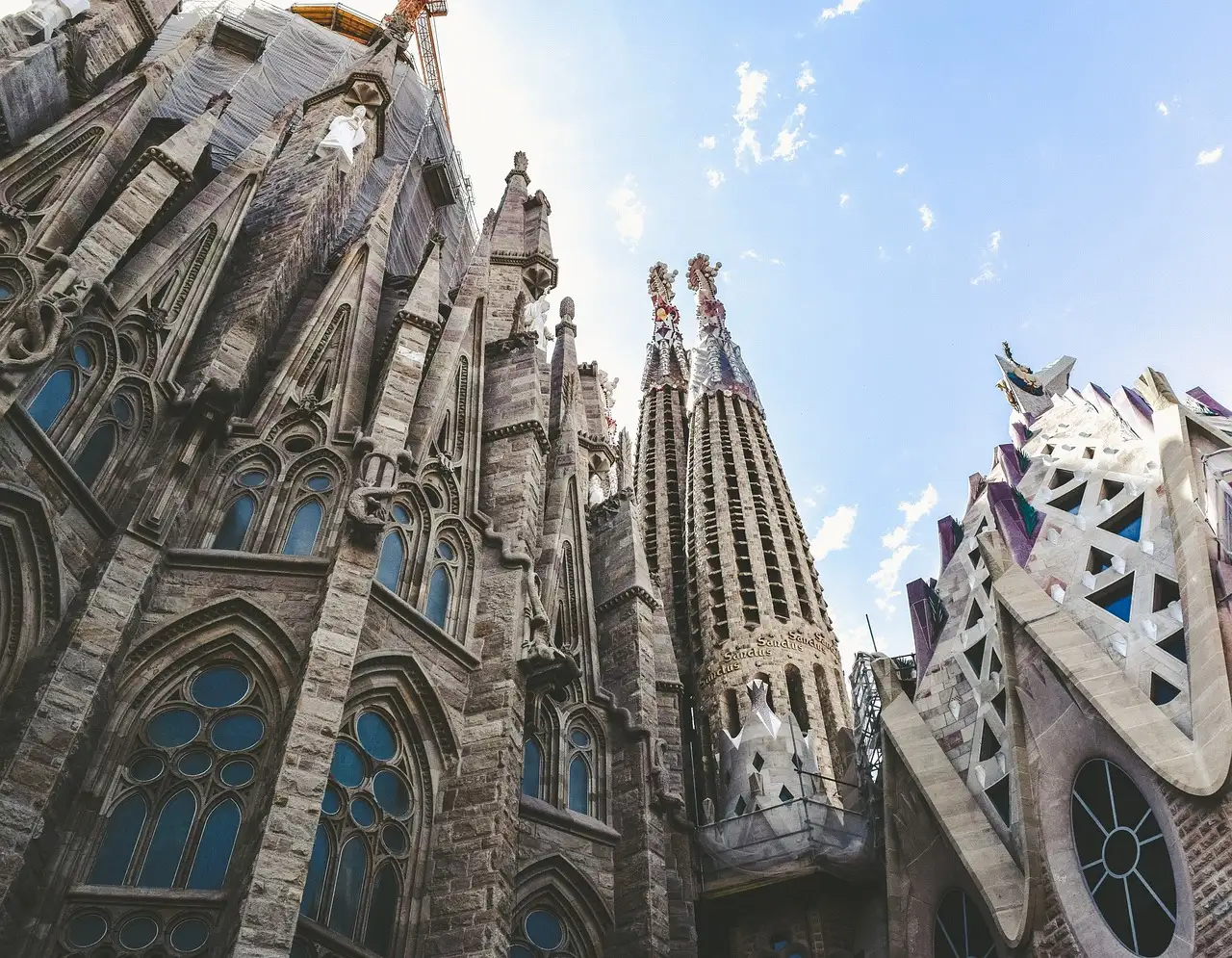 The carved stone towers of the Sagrada Família seen from below against a bright sky