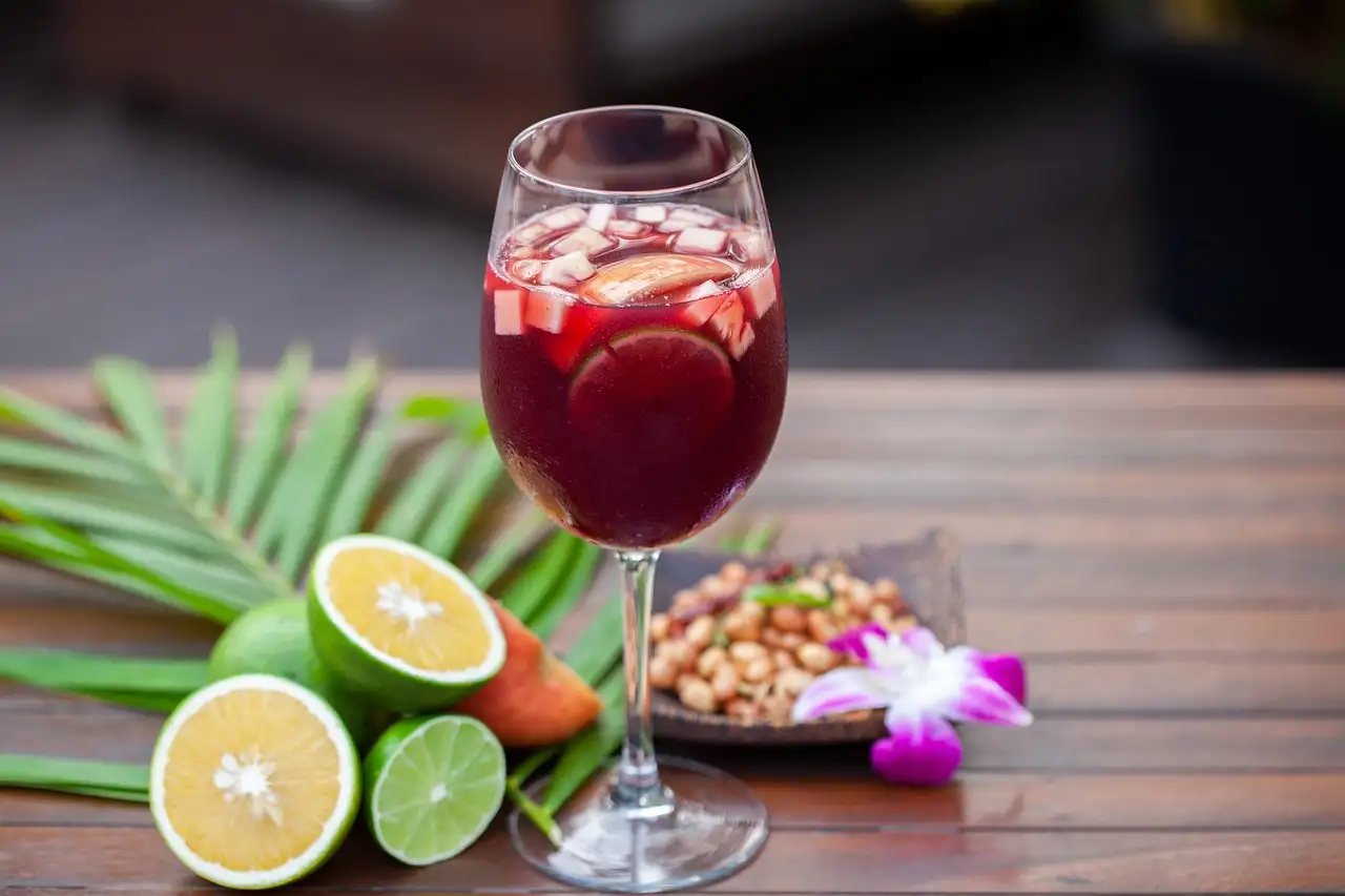 Glass of sangria with fruit next to cut limes